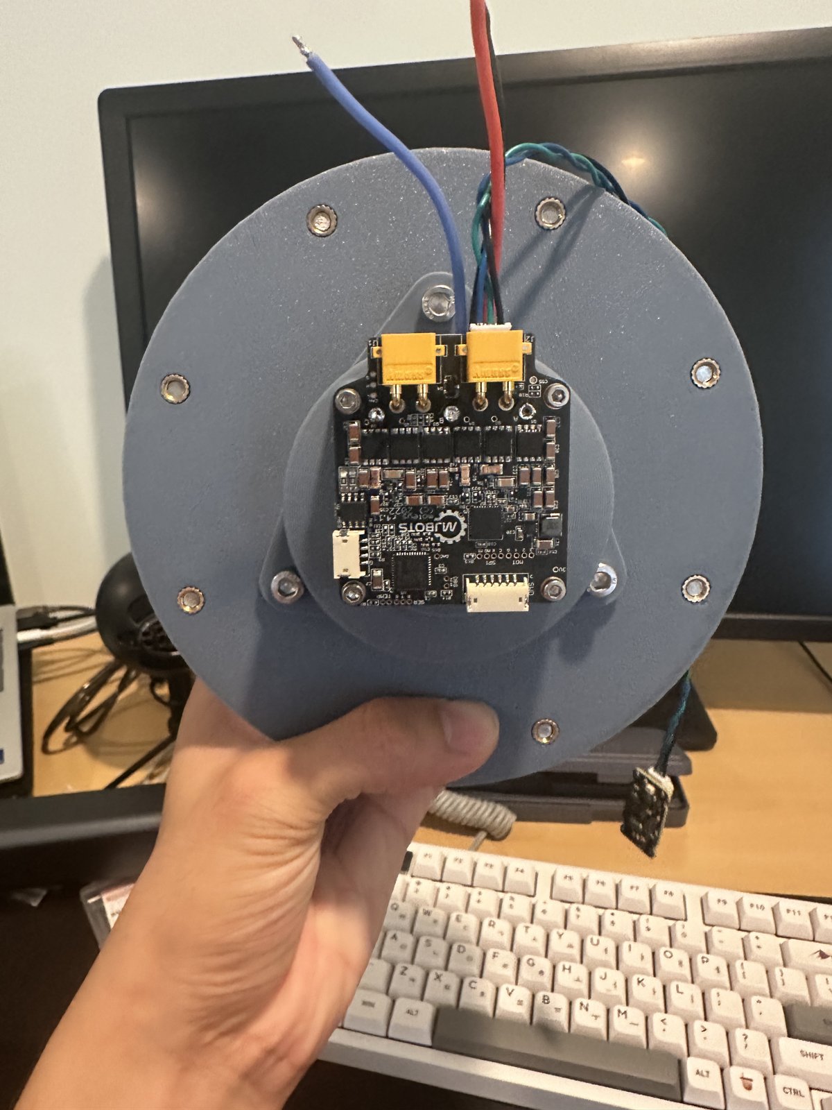 A moteus r4.11 controller mounted on a printed standoff on the back of a cycloidal reducer housing, with power and CAN leads attached