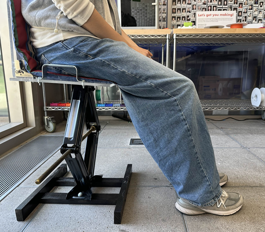 A person seated on the Scissor Seat raised to standing height